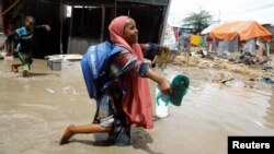 FILE - An internally displaced Somali school girl wades through flood waters outside their makeshift shelter following heavy rains at the Al Hidaya camp for the internally displaced people on the outskirts of Mogadishu, Somalia November 6, 2023 