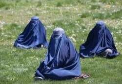 FILE - Afghan women wait to receive free wheat donated by the government during a quarantine, amid concerns about the COVID-19 in Kabul, April 21, 2020.