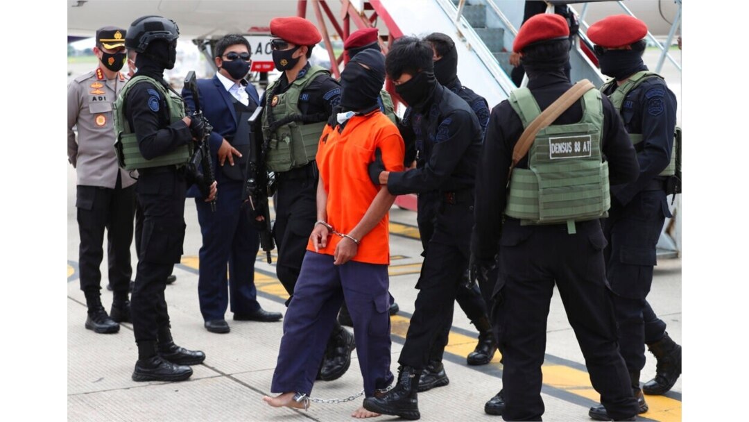 Police officers escort suspected militant Upik Lawanga, center, upon arrival at Soekarno-Hatta International Airport in Tangerang, Indonesia, Dec. 16, 2020.