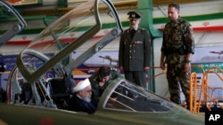 Photo released by official website of the office of the Iranian Presidency shows President Hassan Rouhani being briefed by an air force pilot as he sits in the cockpit of a fighter jet, before an inauguration ceremony of the aircraft, Iran, Aug. 21, 2018.