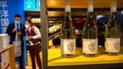 FILE - A staffer and visitor speak near a display of Australian wines at the China International Import Expo in Shanghai, Nov. 5, 2020. China raised import taxes on Australian wine, stepping up pressure on Australia over several disputes.