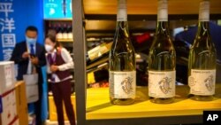 FILE - A staffer and visitor speak near a display of Australian wines at the China International Import Expo in Shanghai, Nov. 5, 2020. China raised import taxes on Australian wine, stepping up pressure on Australia over several disputes.