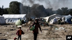 Migrants carry their belongings as they leave from a makeshift camp during a police operation at the Greek-Macedonian border near the northern Greek village of Idomeni, May 26, 2016. 