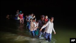 Familias de inmigrantes cruzan una parte baja del Río Grande, antes de ser dejadas por contrabandistas en suelo estadounidense en Roma, Texas, el 24 de marzo de 2021.
