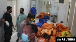 Officers stand near bags containing the bodies of victims of a prison fire at a local hospital, following a fire overnight at an overcrowded jail in Tangerang, Indonesia, Sept. 8, 2021. (Antara Foto/Muhammad Iqbal/via Reuters) 