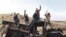 Protesters against the Dakota Access oil pipeline stand on a burned-out truck that they removed from a long-closed bridge on Sunday on a state highway near their camp in southern North Dakota, Nov. 21, 2016. 