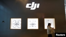 FILE - A woman walks past a store of Chinese drone maker DJI inside a shopping mall in Beijing, Dec. 15, 2021. 