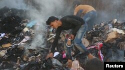 Warga mencari barang-barang dari konvoi lembaga bantuan yang hancur pasca serangan udara Suriah di distrik al-Sakhour, Aleppo, Suriah (4/6). Rusia mengumumkan gencatan senjata baru di Aleppo sejak Rabu (15/6) dini hari. 