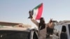 A man with a Sudanese flag gestures following reports that Sudan's army had entered the central city of Wad Madani and pushed out its paramilitary rivals, the Rapid Support Forces, in Merowe, Sudan, Jan.11, 2025.