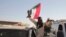 A man with a Sudanese flag gestures following reports that Sudan's army had entered the central city of Wad Madani and pushed out its paramilitary rivals, the Rapid Support Forces, in Merowe, Sudan, Jan.11, 2025.