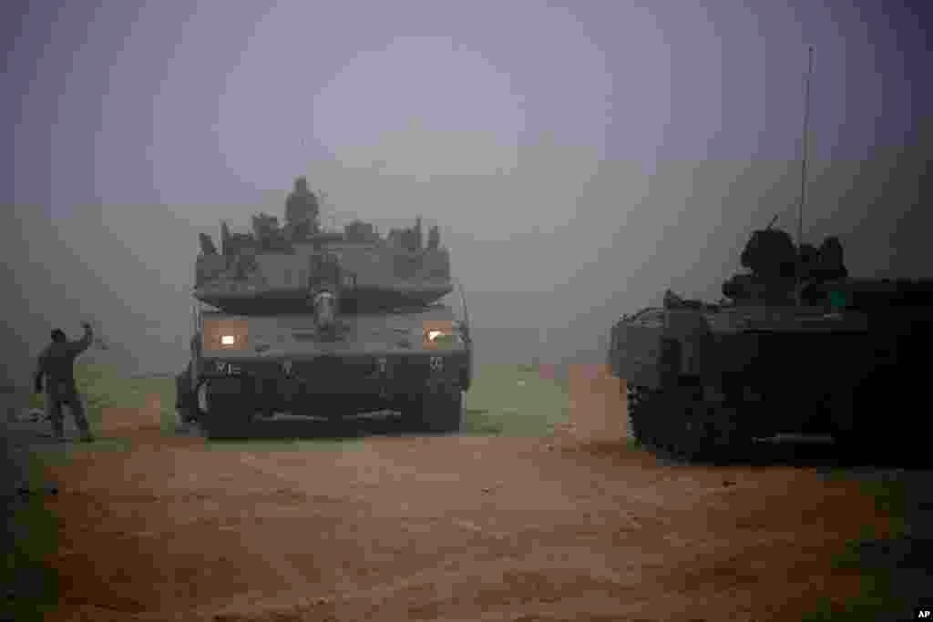 An Israeli tank moves through the morning mist near the Israel and Gaza border, July 24, 2014. 