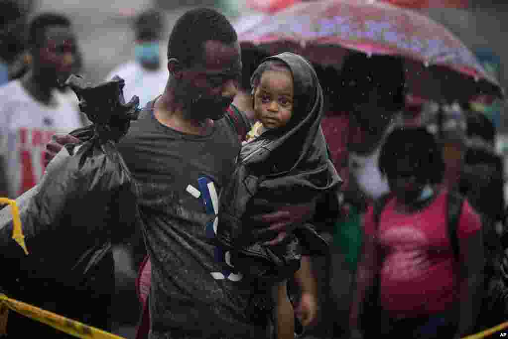 A Haitian migrant carries a baby to a boat that will take them to Capurgana, on the border with Panama, from Necocli, Colombia.