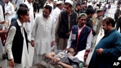 People stand near a man injured from an explosion, at a local hospital in Pakistani tribal area of Parachinar, May 6, 2013.