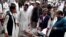People stand near a man injured from an explosion, at a local hospital in Pakistani tribal area of Parachinar, May 6, 2013.