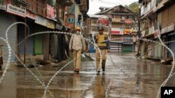 Barbed wires are set up as road blockade as Indian policemen patrol during a strike in Srinagar, Indian-controlled Kashmir, Oct. 19, 2015.