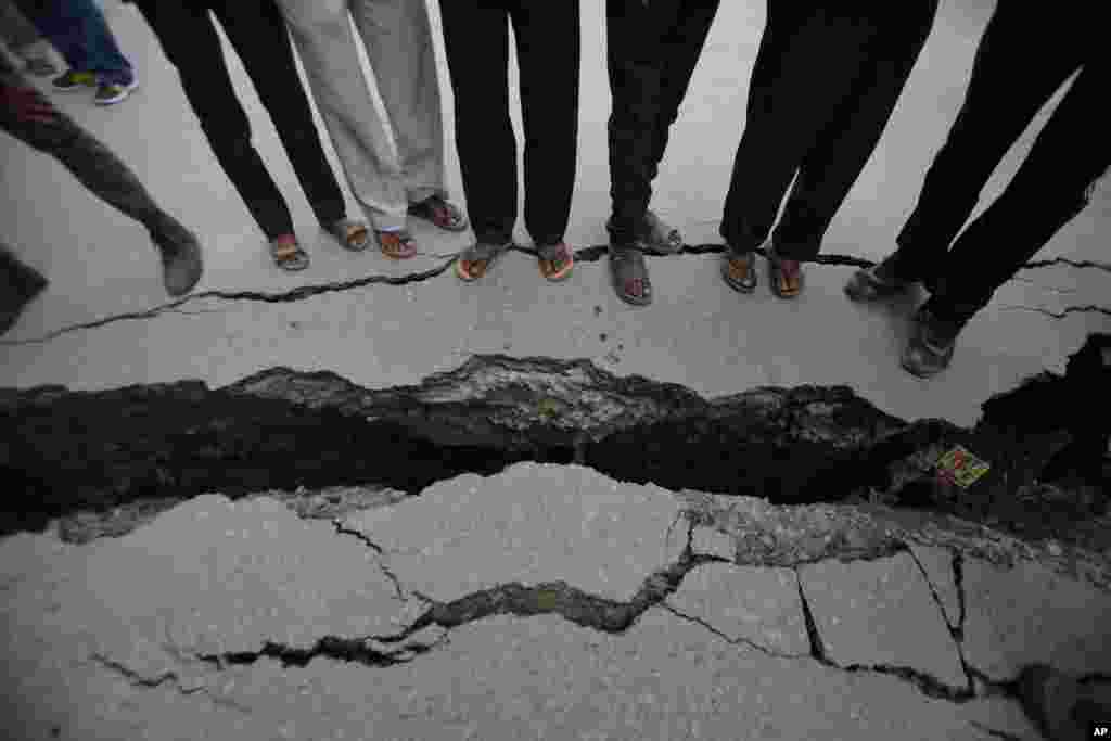 Nepalese people look at a cracked road after an earthquake in Kathmandu, Nepal.