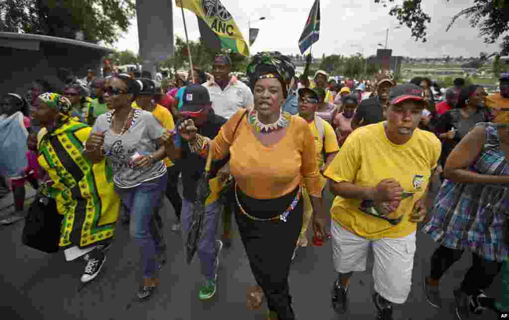 Township residents march to celebrate the life of Nelson Mandela in the street outside his old house in Soweto, Johannesburg, Dec. 6, 2013. 