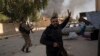 Syrian fighters take position as looters stay inside a building at a residential complex of former Bashar Assad's military officers at the village of Husseiniyeh, in the outskirts of Damascus, Dec. 15, 2024.