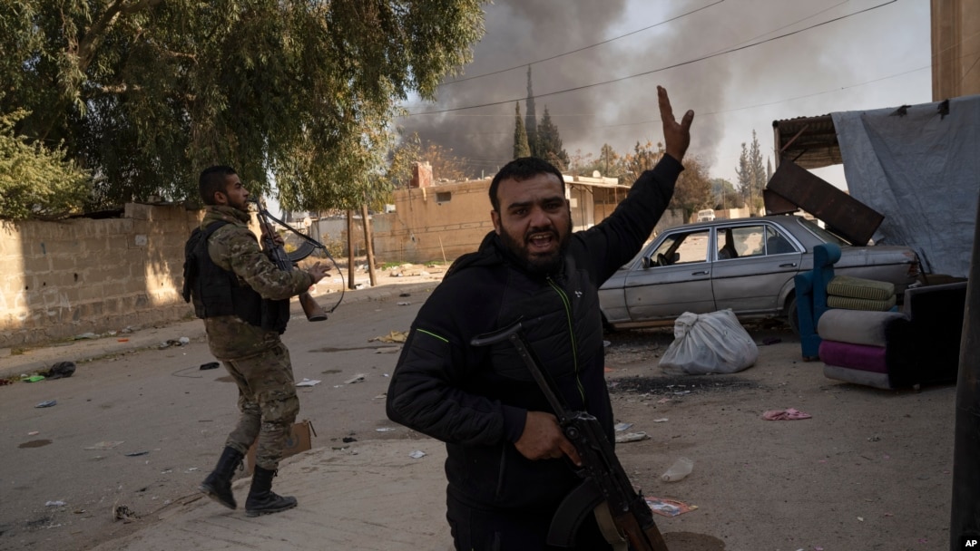 Syrian fighters take position as looters stay inside a building at a residential complex of former Bashar Assad's military officers at the village of Husseiniyeh, in the outskirts of Damascus, Dec. 15, 2024.