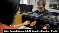 The "rubber hand illusion" has been used in psychological experiments for nearly two decades. Here, at Vanderbilt University, a researcher uses a pair of brushes to test a participant’s perception. (Vanderbilt University / John Russell)