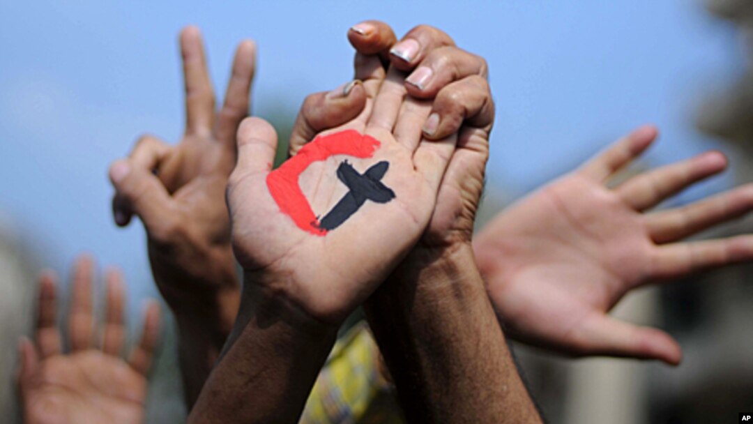 A cross and a crescent are painted on the palm of an Egyptian demonstrator holding the hand of a fellow protester during a rally in support of national unity in Cairo's Tahrir Square on October 14, 2011.