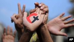 A cross and a crescent are painted on the palm of an Egyptian demonstrator holding the hand of a fellow protester during a rally in support of national unity in Cairo's Tahrir Square on October 14, 2011.