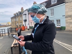 FILE - UK National Health Service employee Anni Adams looks at new NHS app to trace contacts with people potentially infected with the coronavirus disease being tested on Isle of Wight, Britain, May 5, 2020.