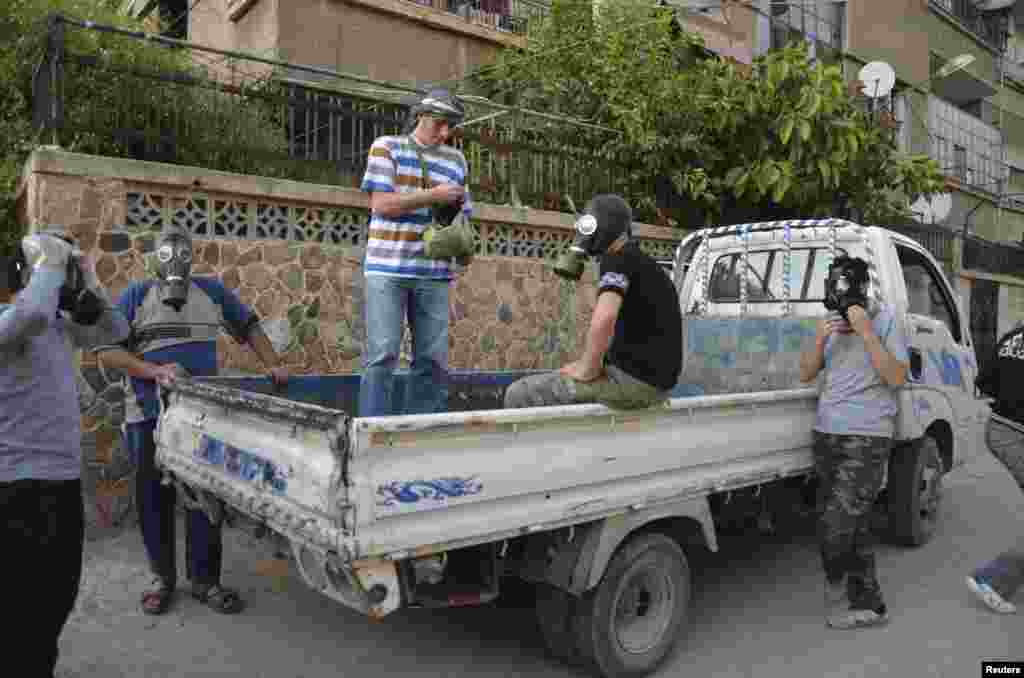 Activists wear gas masks as they look for dead bodies and collect samples to check for chemical weapon use in Zamalka, Damascus, August 22, 2013. 