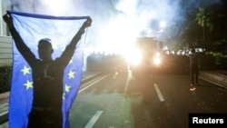 An opposition supporter holds an EU flag outside the Parliament building during an anti-government protest, calling on Prime Minister Edi Rama to step down, in Tirana, Albania, June 8, 2019. 