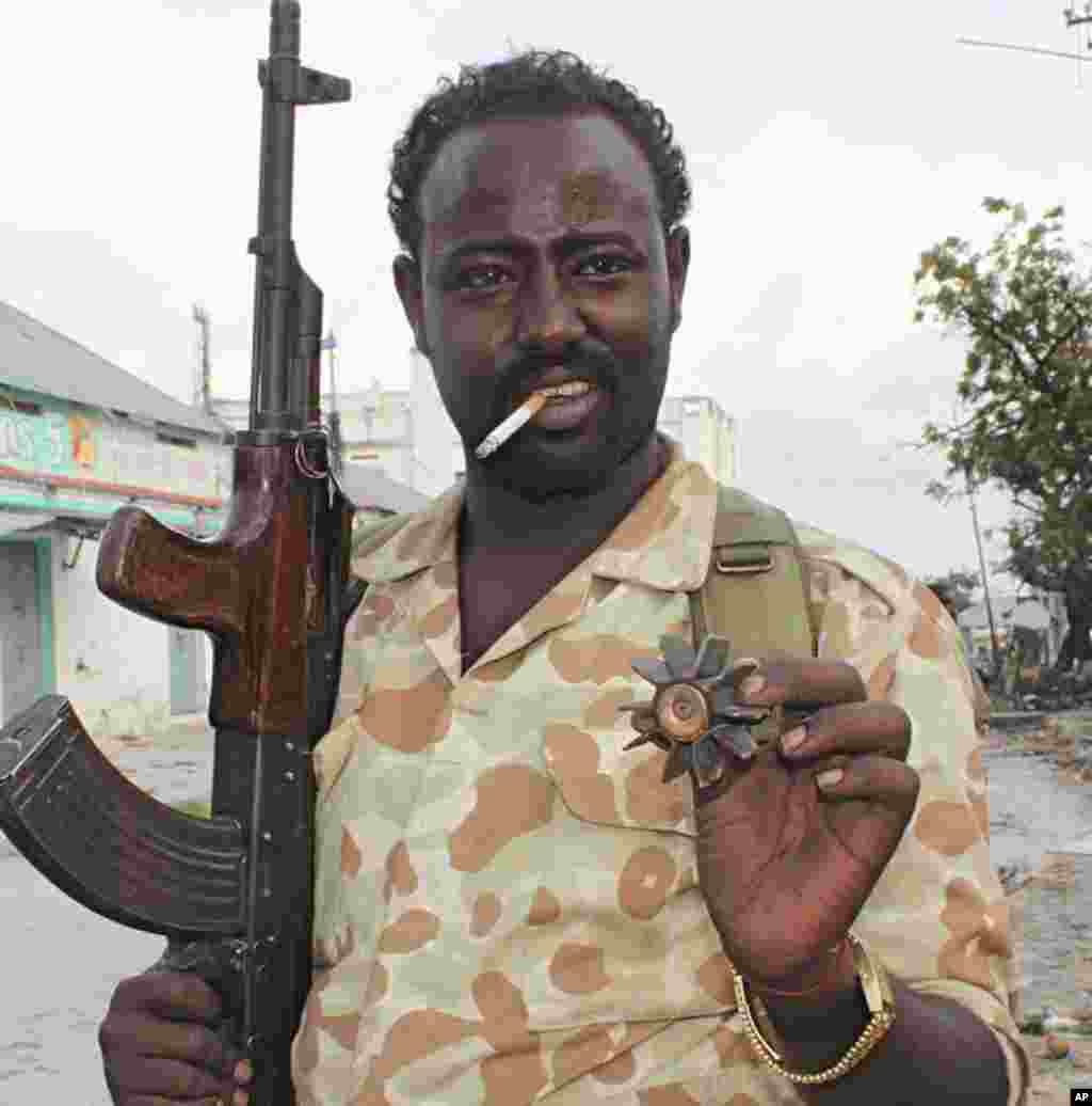 A soldier with cigarette in his mouth shows off spent shell casing found in the rubble (VOA - P. Heinlein)