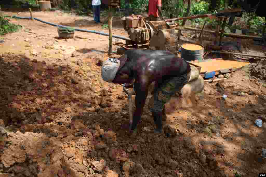 A miner uses a shovel to haul dirt at the Atunso Cocoase small-scale mine in Atunso, Ghana, Oct. 16, 2014. (Chris Stein/VOA)