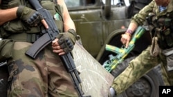 FILE - Pro-Russian rebels hold their guns as they patrol the Lenin square in the town of Donetsk, eastern Ukraine.