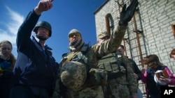 Alexander Hug, chief monitoring mission of OSCE in Ukraine, left, and Ukrainian military servicemen, members of Joint Center for Control and Coordination (JCCC) mission point at a side of the newly installed OSCE surveillance camera to register violations of ceasefire in Avdiivka, eastern Ukraine, April 16, 2016.