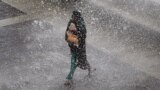 An Indian resident carrying a baby runs from waves on the promenade during a high tide in Mumbai.