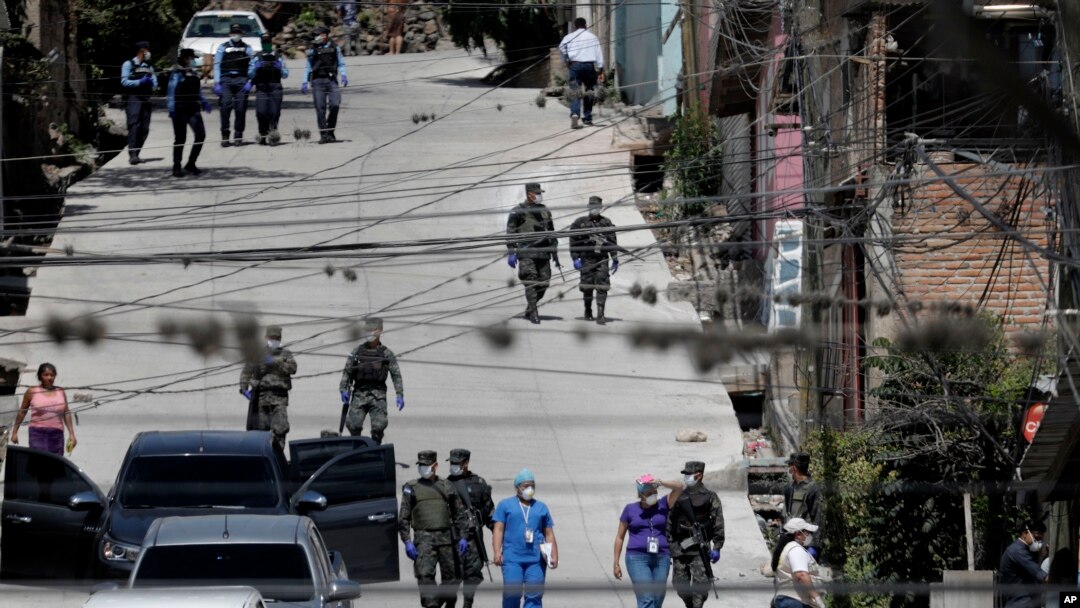 Los trabajadores del Ministerio de Salud están acompañados por soldados y policías mientras investigan en el vecindario acordonado de Lincoln, luego de que varias personas dieron positivo por el nuevo coronavirus, en Tegucigalpa, Honduras.