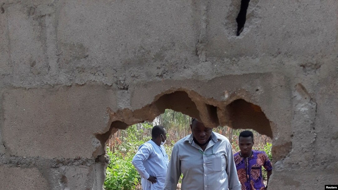 People inspect the broken perimeter wall through which gunmen gained access the male and female hostels at the Federal College in Kaduna, Nigeria, March 12, 2021.