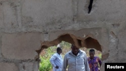 People inspect the broken perimeter wall through which gunmen gained access the male and female hostels at the Federal College in Kaduna, Nigeria, March 12, 2021.