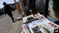 A woman walks past a Beijing newsstand where a newspaper front page shows a photo of Chinese Vice President Xi Jinping and U.S. President Barack Obama, February 16, 2012.