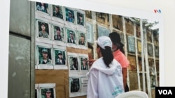 Firmantes del Acuerdo de Paz en Colombia analizan una galería fotográfica con los rostros de antiguos combatientes desaparecidos. Esta imagen de 2023 es parte de la exhibición "El Camino de la Búsqueda", presentada por el Instituto de la Paz de EEUU.