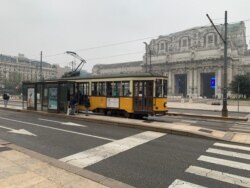 An empty Milan central railway station is seen with an almost empty traditional tram in front of it. (Sabina Castelfranco/VOA)