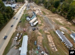 Homes and vehicles that were damaged in a flash flood from Hurricane Helene lie on the side of a road near the Swannanoa River in Swannanoa, North Carolina, Oct. 1, 2024.