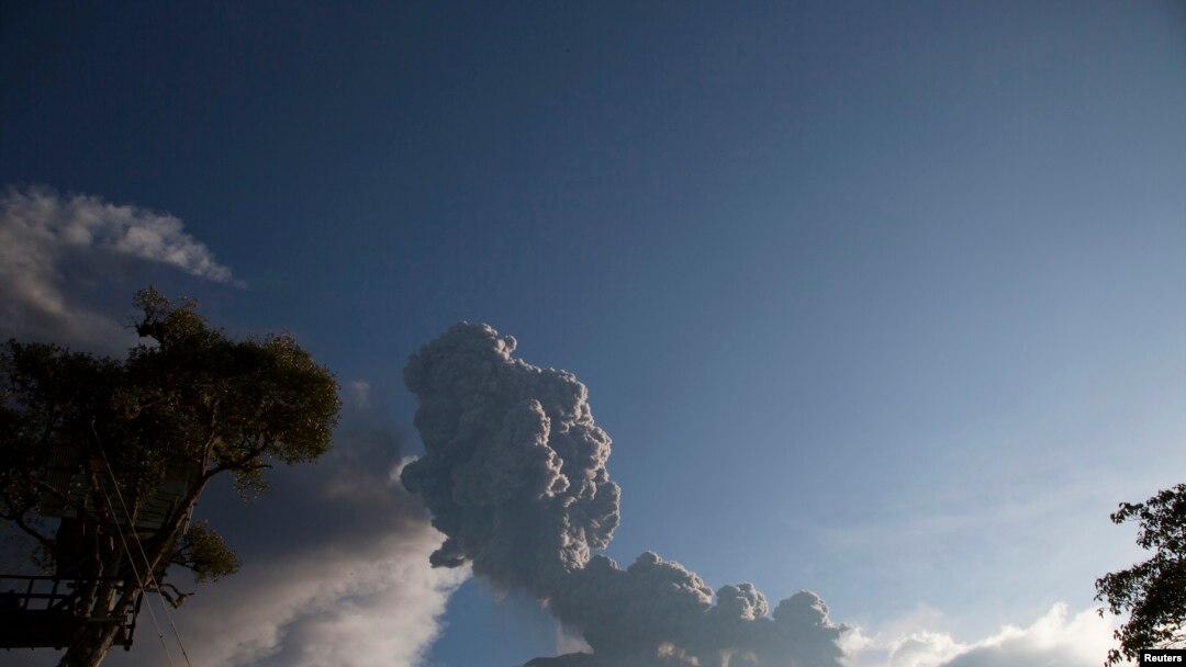 Seorang anak laki-laki bermain ayunan ketika gunung berapi Tungurahua meletus di Banos, 1 Februari 2014. 