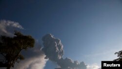 Seorang anak laki-laki bermain ayunan ketika gunung berapi Tungurahua meletus di Banos, 1 Februari 2014. 