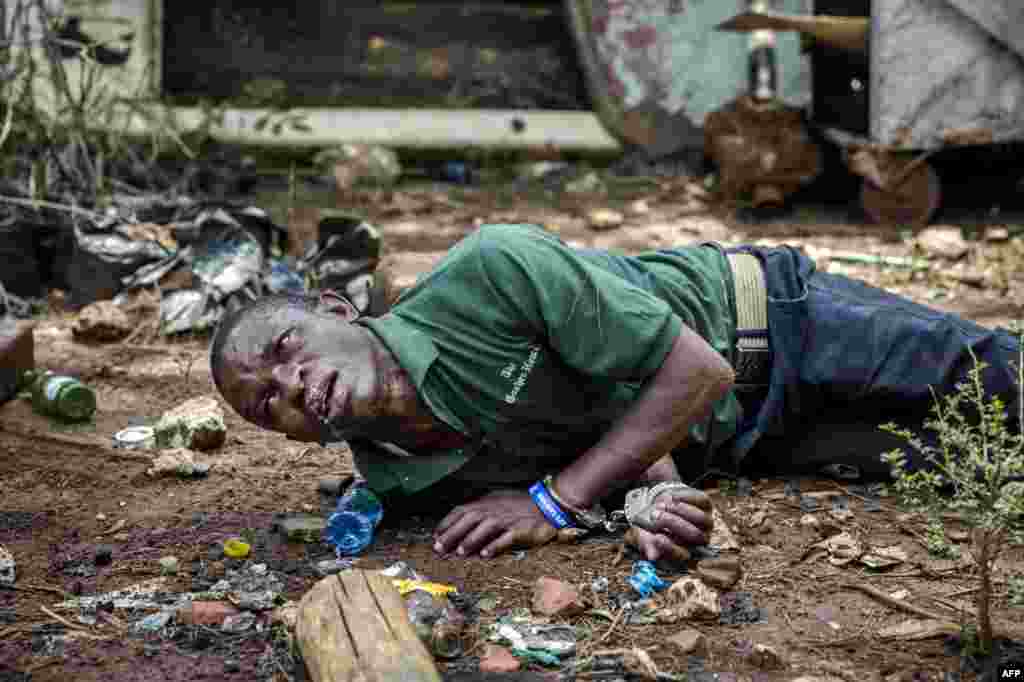 A protester seriously affected by tear gas and allegedly beaten up by police officers lays on the ground with handcuffs on after being arrested in Uhuru Park in Nairobi, Kenya.