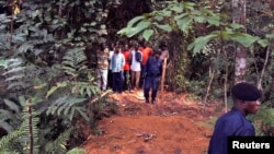 Des policiers encadrent un groupe d’hommes près des tombes nouvellement creusées sur les lieux d'un accident de train dans la jungle à Ndenga Mongo, province du Kasaï, RDC, 4 août 2007.