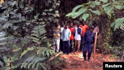 Des policiers encadrent un groupe d’homme près des tombes nouvellement creusées sur les lieux d'un accident de train dans la jungle à Ndenga Mongo, province de Kasaï, RDC, 4 août 2007. 