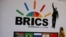 FILE - A delegate walks past a BRICS logo ahead of the 10th BRICS Summit, in Sandton, South Africa, July 24, 2018. 