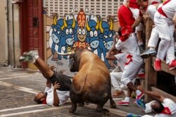 FILE - A reveler is gored by a Cebada Gago's ranch fighting bull during the running of the bulls in Pamplona, Spain.