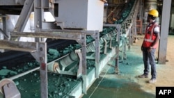 A man watches a conveyor belt loaded with chunks of raw cobalt after a first transformation at a plant in Lubumbashi, Congo, on Feb. 16, 2018, before being exported, mainly to China, to be refined.