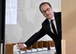 FILE - French president Francois Hollande picks up ballots before voting in the first round of the presidential election in Tulle, central France, Apr. 23, 2017.